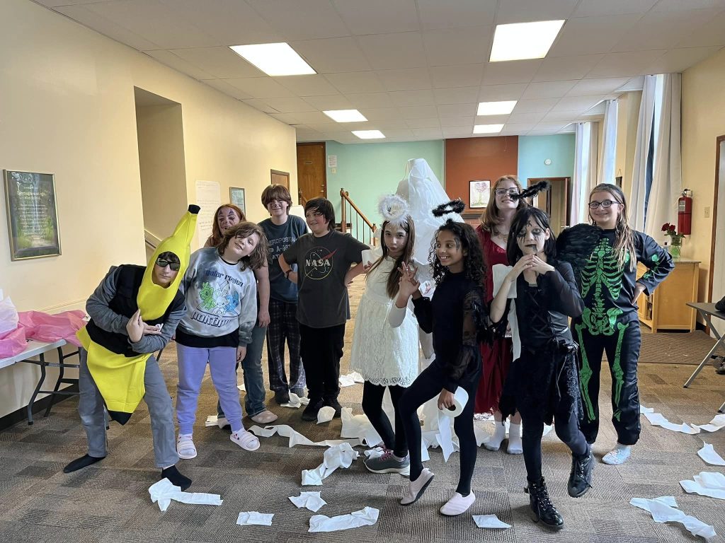Students posing together in Halloween costumes in the hallway.